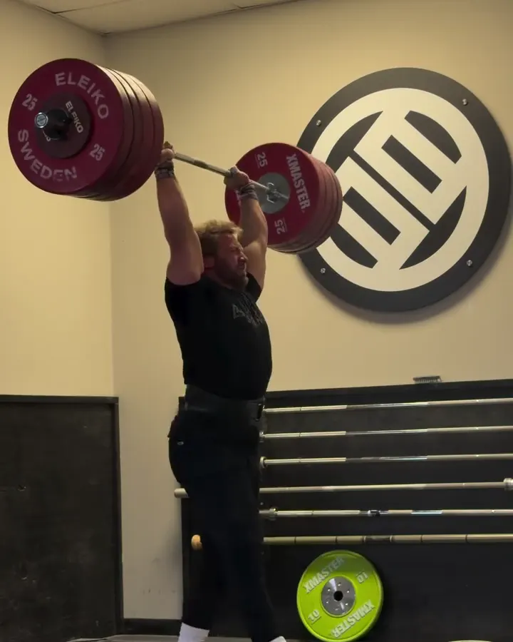 Wes Kitts locks out his 225kg (496lb) clean and jerk in front of the BE SOMEBODY wall.